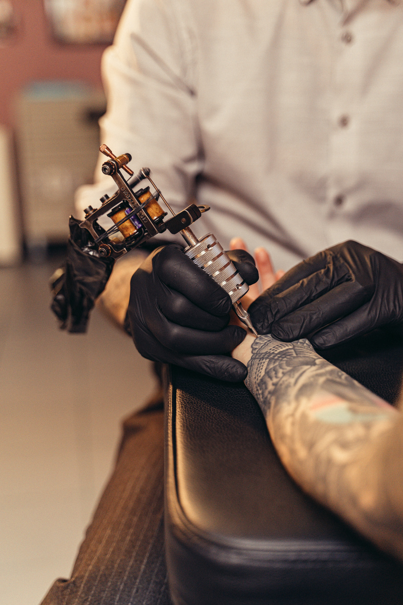 A Tattoo Artist Tattooing a Client's Arm